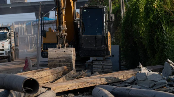 Excavadora Amarilla Estacionada Sitio Construcción Con Camión Borroso Conduciendo Carretera — Foto de Stock