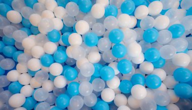 Çocuk parkındaki top havuzunda mavi ve beyaz plastik toplar. Renkli plastik top dokusu arka planı. Bir sürü küçük renkli, içi boş plastik, yumuşak çocuk topları bir top havuzunda. Çocuklar için oyuncak oyna.