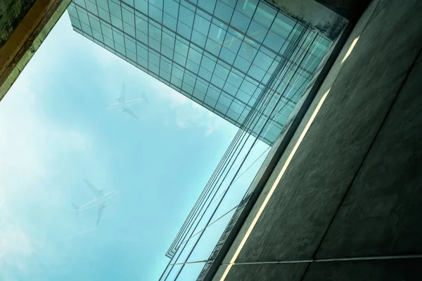 从底层俯瞰现代可持续的玻璃办公楼和蓝天的飞机 公司总部玻璃建筑的外部视野 节能建筑 玻璃窗 — 图库照片