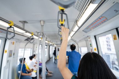 Yükseltilmiş raylı trendeki kadın el sıkışık emniyet korkuluğu. Modern şehirde toplu taşıma sistemi. Elektrikli trenin içinde. Gökyüzü treniyle seyahat eden turistler. Toplu taşıma. Şehir ulaşımı.