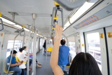 Yükseltilmiş raylı trendeki kadın el sıkışık emniyet korkuluğu. Modern şehirde toplu taşıma sistemi. Elektrikli trenin içinde. Gökyüzü treniyle seyahat eden turistler. Toplu taşıma. Şehir ulaşımı.