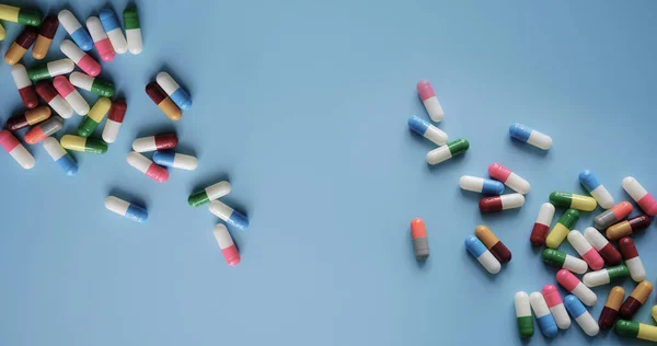 Top view colorful antibiotic capsule pills on blue background. Online pharmacy banner. World Health Day. Pharmaceutical industry. Prescription drugs. Antibiotic drug resistance concept. Health care.