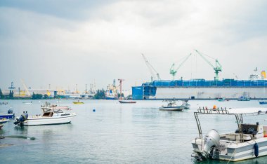 Büyük gemi yoğun limana huzurlu bir şekilde yanaştı. Denizcilik lojistiği ve taşımacılığın hayati rolü. Limandaki ticari gemilerde küresel taşımacılık ve lojistik ürünleri sergileniyor. Ulaşım ve denizcilik endüstrisi.