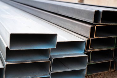 İnşaat malzemeleri ve inşaat malzemeleri için sanayi deposu dikdörtgen metal borular. Çelik borular yığını. İnşaat ve altyapı projeleri için demir malzemeler. Çelik boru deposu.