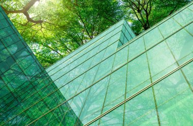 Modern şehirde çevre dostu bir bina. Karbondioksiti azaltmak için ağaçlı sürdürülebilir cam ofis binası. Yeşil çevresi olan bir ofis binası. Şirket binası karbondioksiti azaltır. Sıfır ağ emisyonu