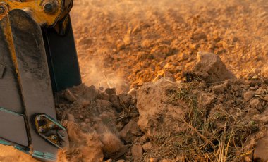 Metal kepçe kazıcı toprak kovası. İnşaat alanında çalışan kazıcı. Toprak hareket makinesi. Kazı aracı. Ağır makineler iş başında. İnşaat makineleri ve toprak taşıma ekipmanları.