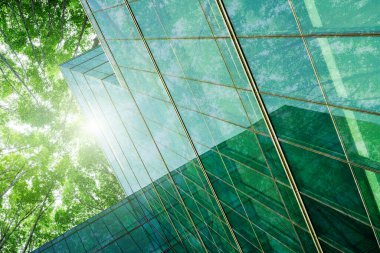 Modern şehirde çevre dostu bir bina. Isı ve karbondioksiti azaltmak için ağaç olan sürdürülebilir cam ofis binası. Yeşil çevresi olan bir ofis binası. Şirket binası CO2 'yi düşürdü.