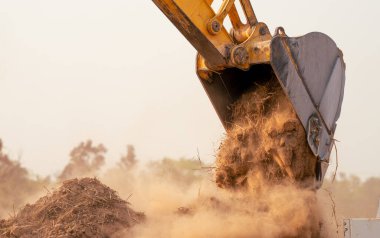 Yeni geliştirme projesi Dünya Hareket Makinesi için toprak döşeyen inşaat alanı kazıcı kovasında toprak kazarak çalışan kepçe. İnşaat projesi üzerine vakıf çalışması.