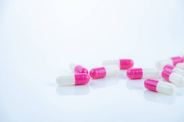 Beyaz arka plana yayılmış pembe-beyaz antibiyotik kapsüller. Reçeteli ilaç. Modern tıpta antibiyotik direnci. Sağlık ve eczacılık endüstrisi. Tıbbi bakım, ilaç araştırması..