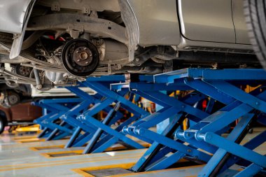 Otomobil diski fren sistemi ve tamirat atölyesinde lastik değiştirme sırasında süspansiyon bakımı. Araç güvenliği ve performans optimizasyonu için otomotiv onarımı ve profesyonel mekanik hizmetleri.