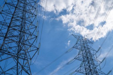 Gökyüzüne karşı elektrik hatları olan yüksek voltajlı elektrik iletim kulesi, elektrik arzı, sanayi altyapısı, enerji dağılımı ve enerji krizinin zorluklarını vurguluyor.