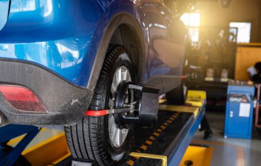 Wheel alignment equipment grip the tire of car wheel in car repair shop. Auto wheel alignment in workshop of service station. Car wheel balance. Suspension adjustment. Vehicle inside garage workshop.
