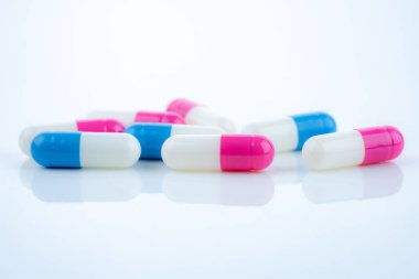 Beyaz arka plana yayılmış mavi ve pembe kapsül hapları, ilaç ürünlerinin sergilenmesi, sağlık hizmetleri kavramları ve reçeteli ilaçların ilerlemekte olan tedavi ve hastanın refahında rolü.