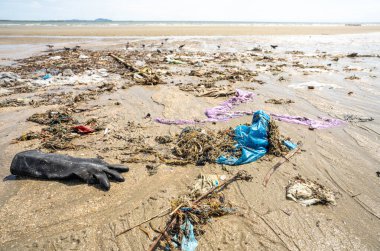 İnsan atıkları, kıyı şeridine yayılmış plastik torbalar ve enkazlarla tropikal bir plajı kaplıyor. Küresel deniz kirliliği krizi ve çevresel kirlilik. Plaj kirliliği krizi. Okyanus atıkları.