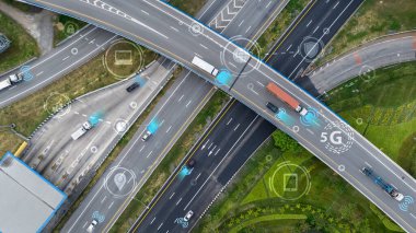 Otonom araçlar ve bağlantı sembolleriyle modern otoyol kavşağının havadan görünüşü. Akıllı trafik sistemleri ve gelecekteki ulaşım ve akıllı hareketlilik çözümleri için 5G teknolojisi.