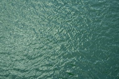 Sakin su yüzeyinin yumuşak doğal dalgalanmalarla üst görüntüsü. Çevre dostu tasarım, barışçıl kavramlar ve su sürdürülebilirliği için arka plan. Gökyüzü görüntüsü mavi yeşil göl yüzey su arkaplanı.