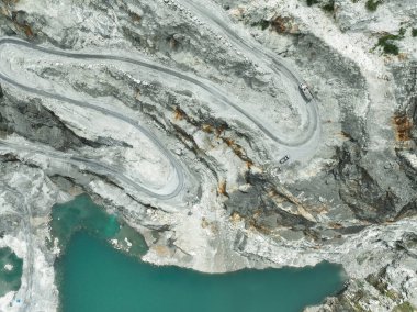 Taş çıkarma sırasında teraslı taş ocağı katlarında hareket halindeki hava görüntüleme kamyonu. Madencilik teknolojisi, arazi kullanımı dönüşümü ve ağır sanayide kurumsal sorumluluk. Açık maden endüstrisi.