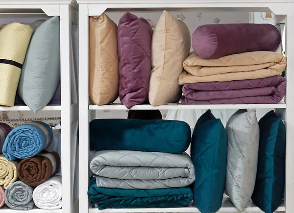 色彩斑斓的枕头 床单和其他床上用品站在架子上 — 图库照片