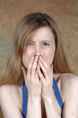 Young woman holding hand across mouth to hide disgust expression on her face