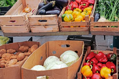 Karton içinde taze organik sebzeler ve market tezgahında ahşap sandıklar.
