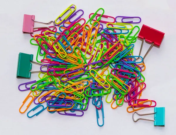 Colrful metal paper clips and pins pile on white background