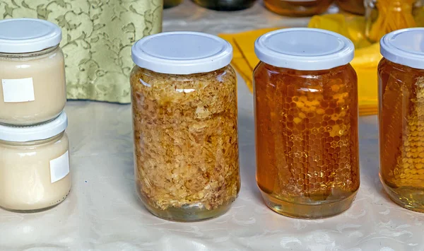Royal jelly honey comb and other bee products in glass jars sold on market stall