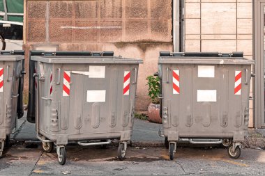 Şehir caddesinde kapalı metal çöp konteynerleri.