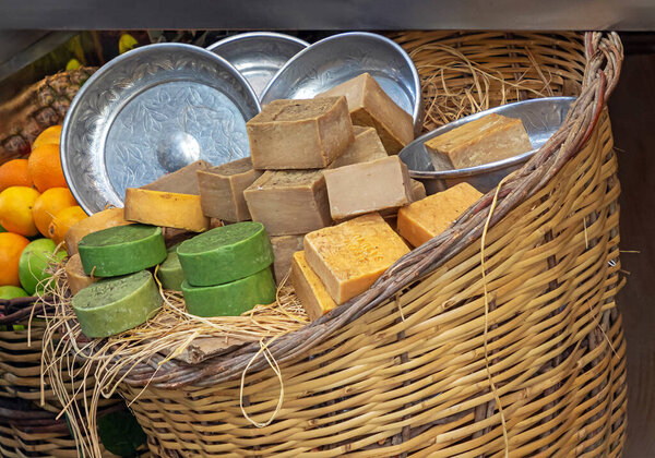 Organic handmade soaps pile inside rattan basket outside on a market