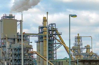 Otoyolun kenarındaki bacadan duman çıkan modern petrol endüstrisi binaları