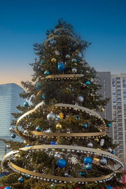 Şehir sokağında parlak altın süslerle süslenmiş Noel ağacı.