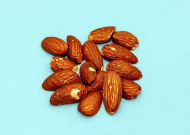 Mavi zemin üzerinde organik kavrulmuş badem yığını.