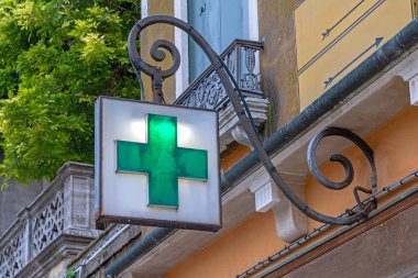 Caddedeki bina cephesinde parlayan yeşil haç eczanesi tabelası.