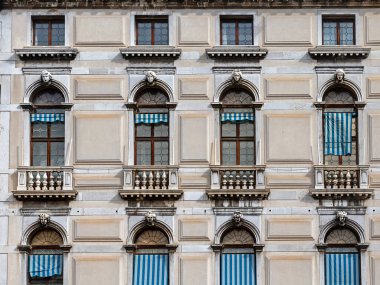 Kapalı pencereleri ve taş balkonları olan eski bir cephe.