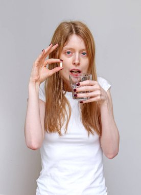 Genç hasta kadın bir bardak suyla hap alıyor.