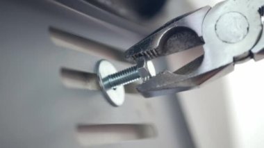 close up view mechanician use pliers tighten a bolt of the car's license plate on the car.install license plate