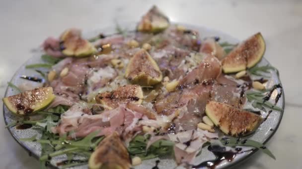 イチジクと松の実のサラダと自家製の新鮮なパルマハムのプレートにオリーブオイルを注ぐイタリアの伝統的な食品前菜 — ストック動画