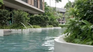 30 Eylül 2022: Phangnga, Tayland: Sıcak, gevşek yüzme havuzu manzarası modern tasarım tesislerinde tropikal ağaçlarla birlikte kasvetli hava zamanıyla