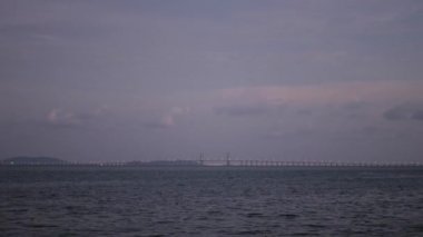 Penang Köprüsü 'nün deniz üzerindeki manzarası araba trafiği gün batımında deniz kıyısına yakın parktan otoyola çıkıyor.