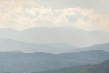 Güneşli dağların katmanlarındaki sisli dağların havadan görünüşü, doğal arka plan.