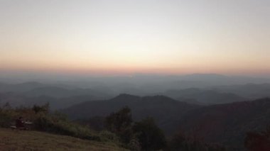 Günbatımı manzaralı dağ manzarası. Biraz bulutlu. Kış zamanı tepedeki dağdan günbatımına doğru gökyüzüne karşı dağ ormanı silueti.