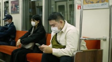 16 Kasım 2022: Fukuoka, Japonya: Japonya 'da Japon toplu tren taşımacılığı sırasında banliyö treninde oturan Asyalı yolcu