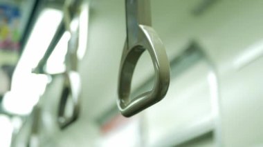 İnsan yolcu eli metro banliyö vagonunda asılı duruyor. Hareket halindeyken, Japon toplu taşımacılığı.