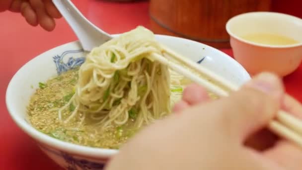 お箸でとんこつラーメンをつかみ 温度を下げるために持ち上げてください 中華麺 日本全国のラーメン丼熱いスープ — ストック動画