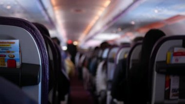 Rahatlarken yolcu dolu uçak kabininin içinde dar bir koridor var. İnsanlar jet uçağıyla tanınmayan yolcularla rahat koltuklarda seyahat ediyorlar.