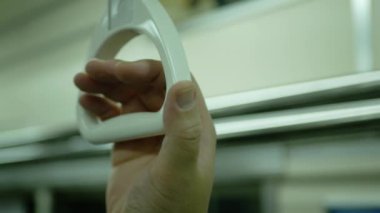 Close up of Hands holding handrail or grip straps in metro train, passenger hand holds hanging handrail in subway commuter train car public train sportation while moving