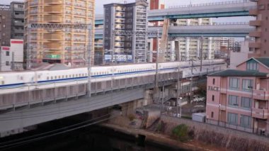 November 15,2022:Fukuoka,Japan:train railway track JR with highspped Bullet Train Shinkansen among landscape view of the hakata habitat housing building city area with sunrise early morning sky