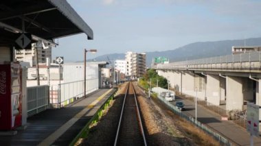 November 14,2022:Fukuoka,Japan:Train journey point of view from on the rear back view of train commuter car Railway Track Seen from Train Perspective POV leaving from flatform station in japan