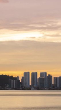 Deniz kıyısındaki yüksek gökdelen binalı liman manzaralı dikey zaman çizelgesi silueti. Gün batımı, alacakaranlık gökyüzü ve gökyüzünde hareket eden bulutlu manzara.