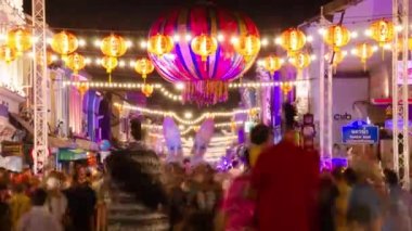 January 27,2023:Phuket old town,Thailand: timelapse landscape night view with light illumination on the colonial architecture building with crowded people in Phuket Festival 2023 night time
