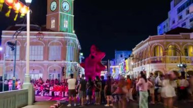 January 27,2023:Phuket old town,Thailand: timelapse landscape night view with light illumination on the colonial architecture building with crowded people in Phuket Festival 2023 night time